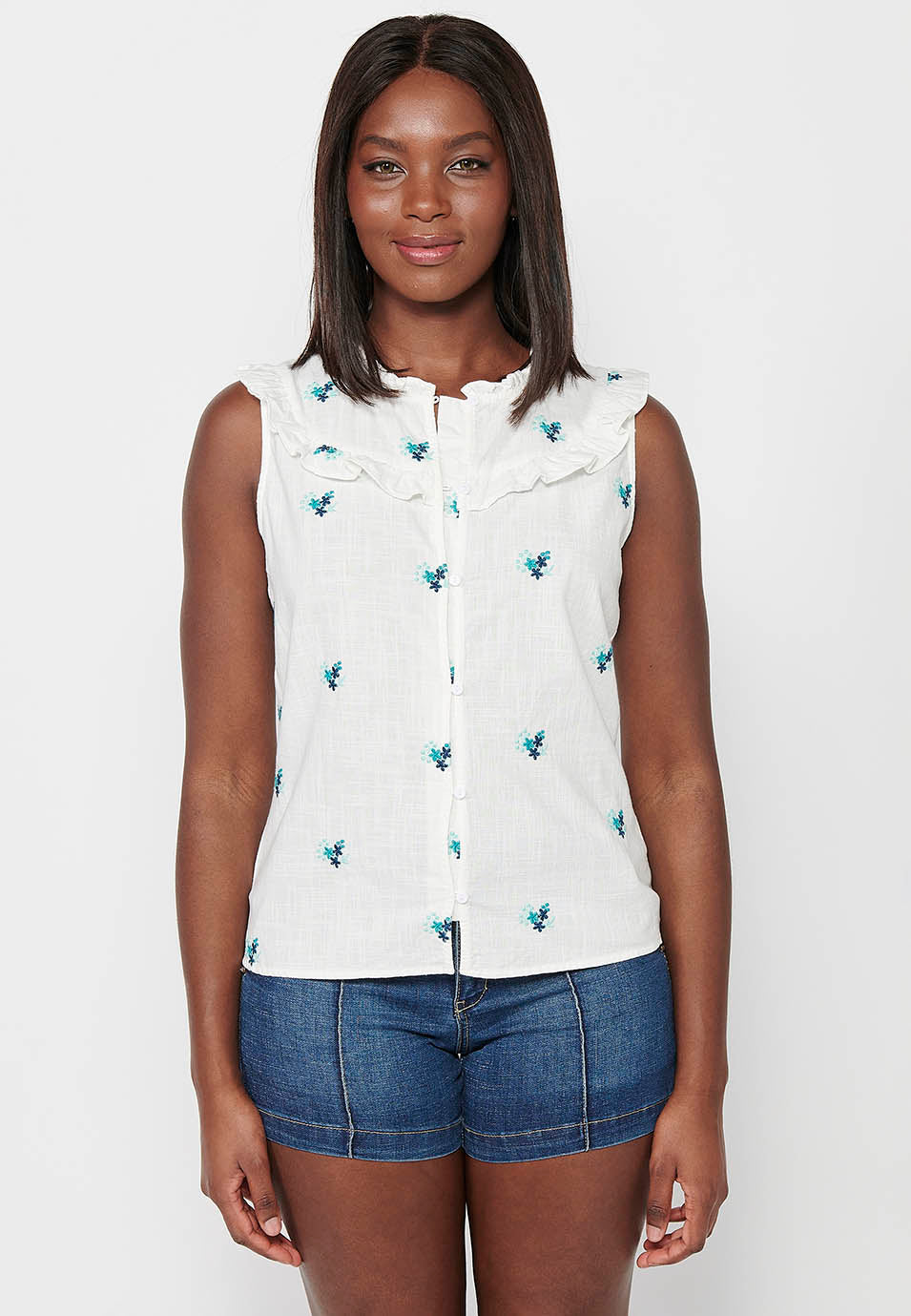 Blusa sin mangas de algodón de mini volante en los hombros con tela con bordados florales y cuello redondo y cierre delantero con botones elásticos para mujer | moda actual