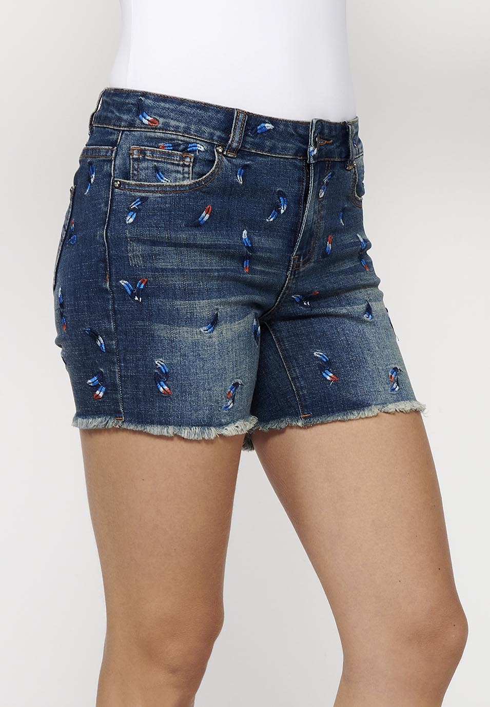 Pantalón corto denim con cierre delantero con cremallera y botón y tela con bordados con cinco bolsillos, uno cerillero para mujer | moda actual