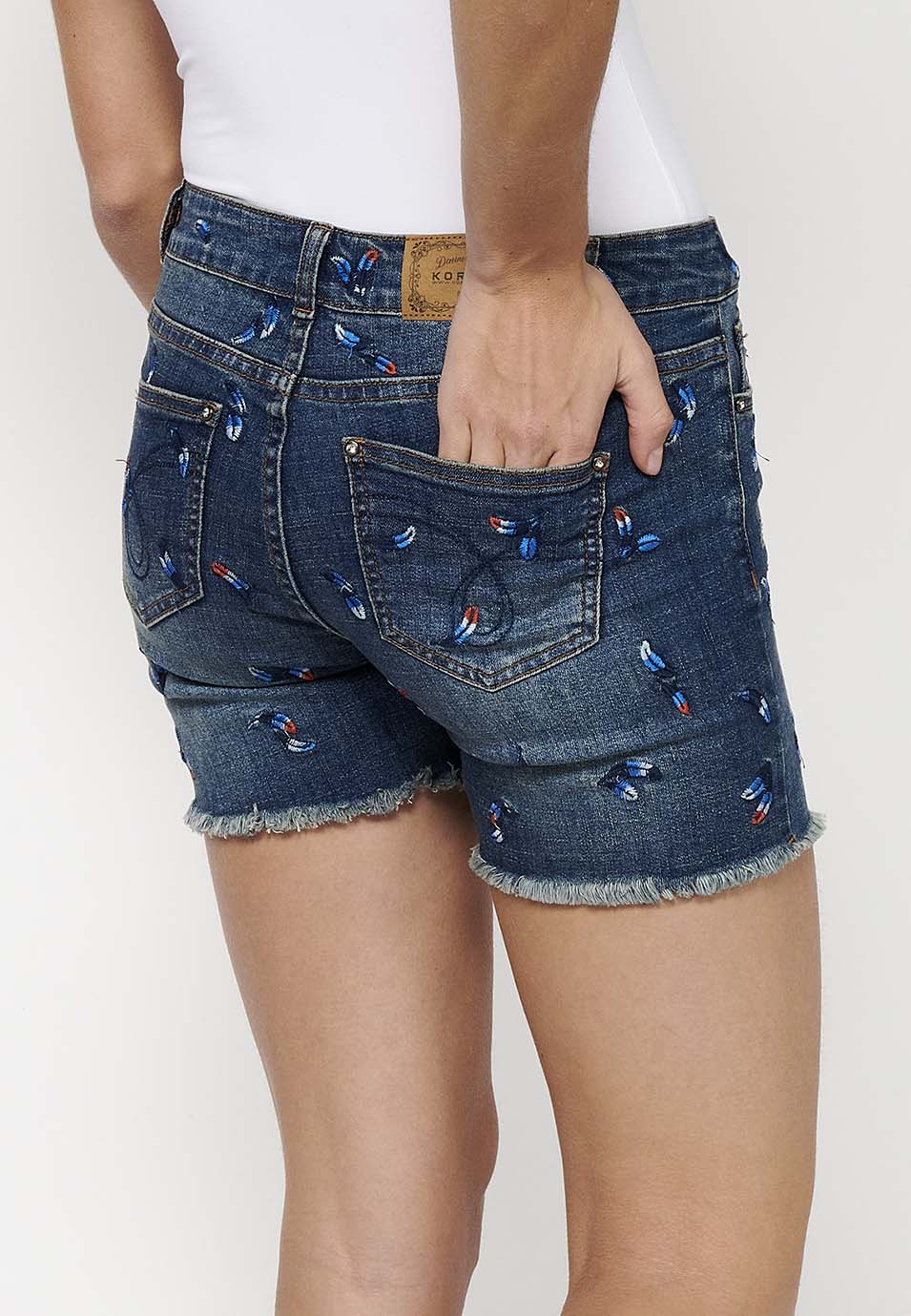 Pantalón corto denim con cierre delantero con cremallera y botón y tela con bordados con cinco bolsillos, uno cerillero para mujer | moda actual