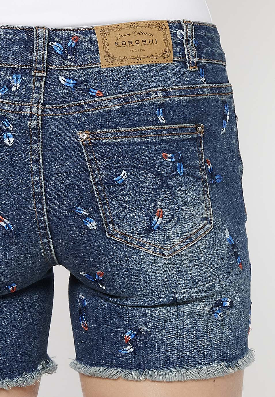 Pantalón corto denim con cierre delantero con cremallera y botón y tela con bordados con cinco bolsillos, uno cerillero para mujer | moda actual