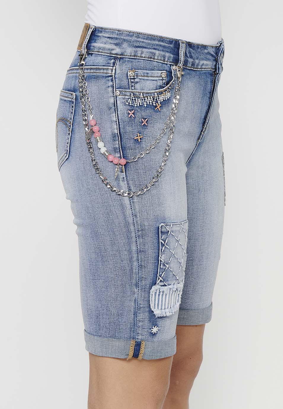 Pantalón corto short acabado en vuelta con detalles de parches delanteros y cadena adorno extraíble con cierre delantero con cremallera y botón para mujer | moda actual