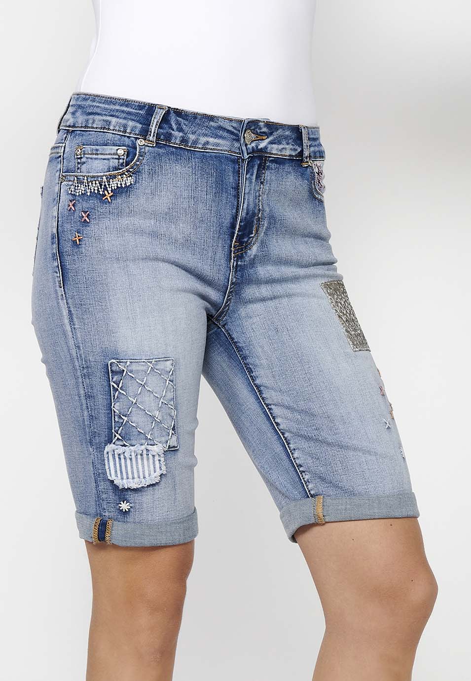Pantalón corto short acabado en vuelta con detalles de parches delanteros y cadena adorno extraíble con cierre delantero con cremallera y botón para mujer | moda actual