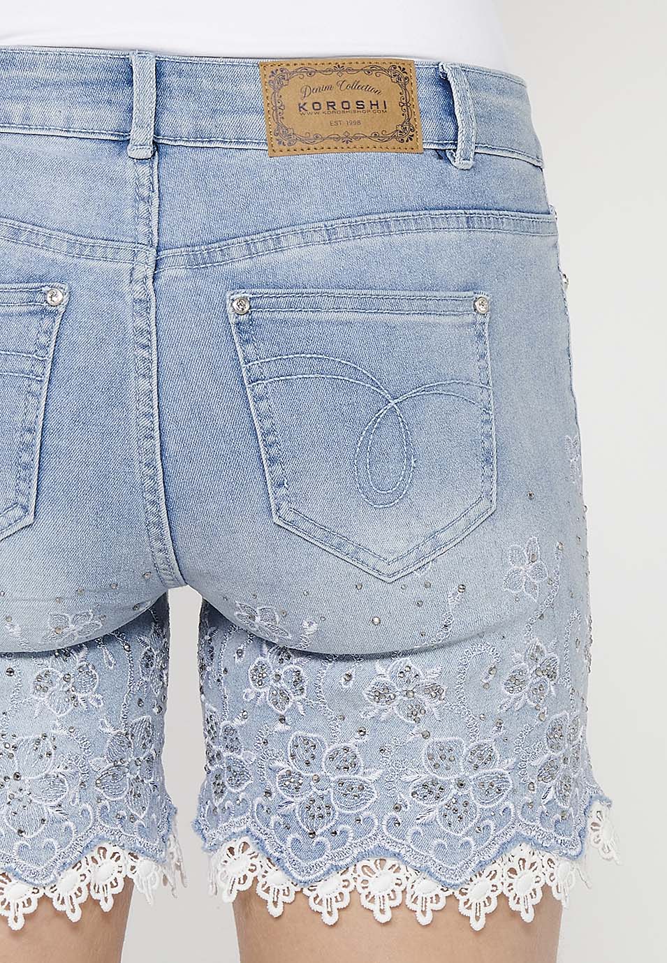 Pantalón corto short denim acabado con encaje y bordado floral con cierre delantero con cremallera y botón con detalle lazo extraíble para mujer | moda actual