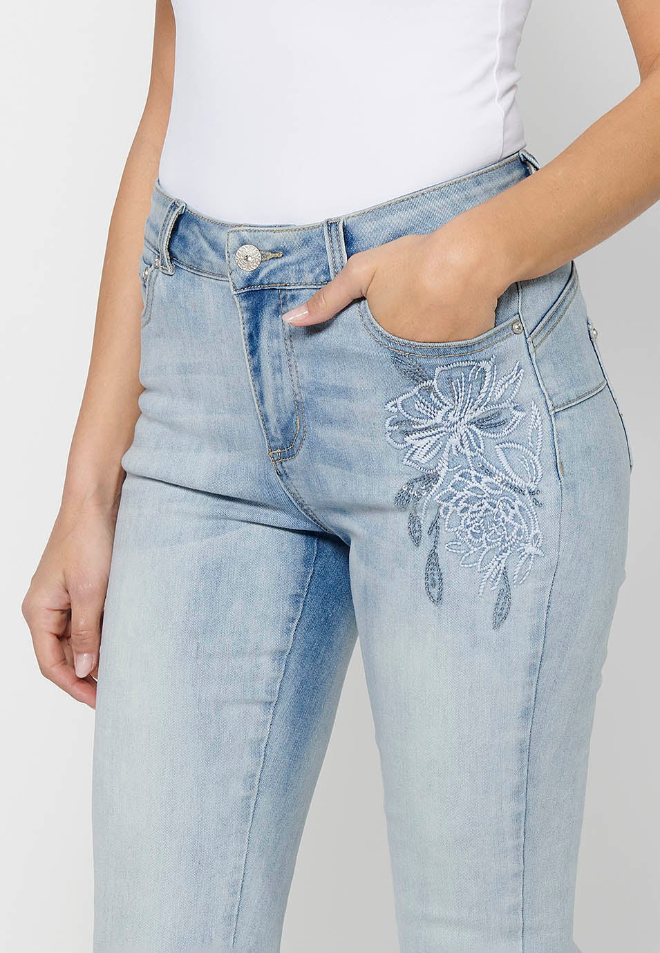 Pantalón largo slim con cierre delantero con cremallera y botón con detalles bordados de claro para mujer | moda actual