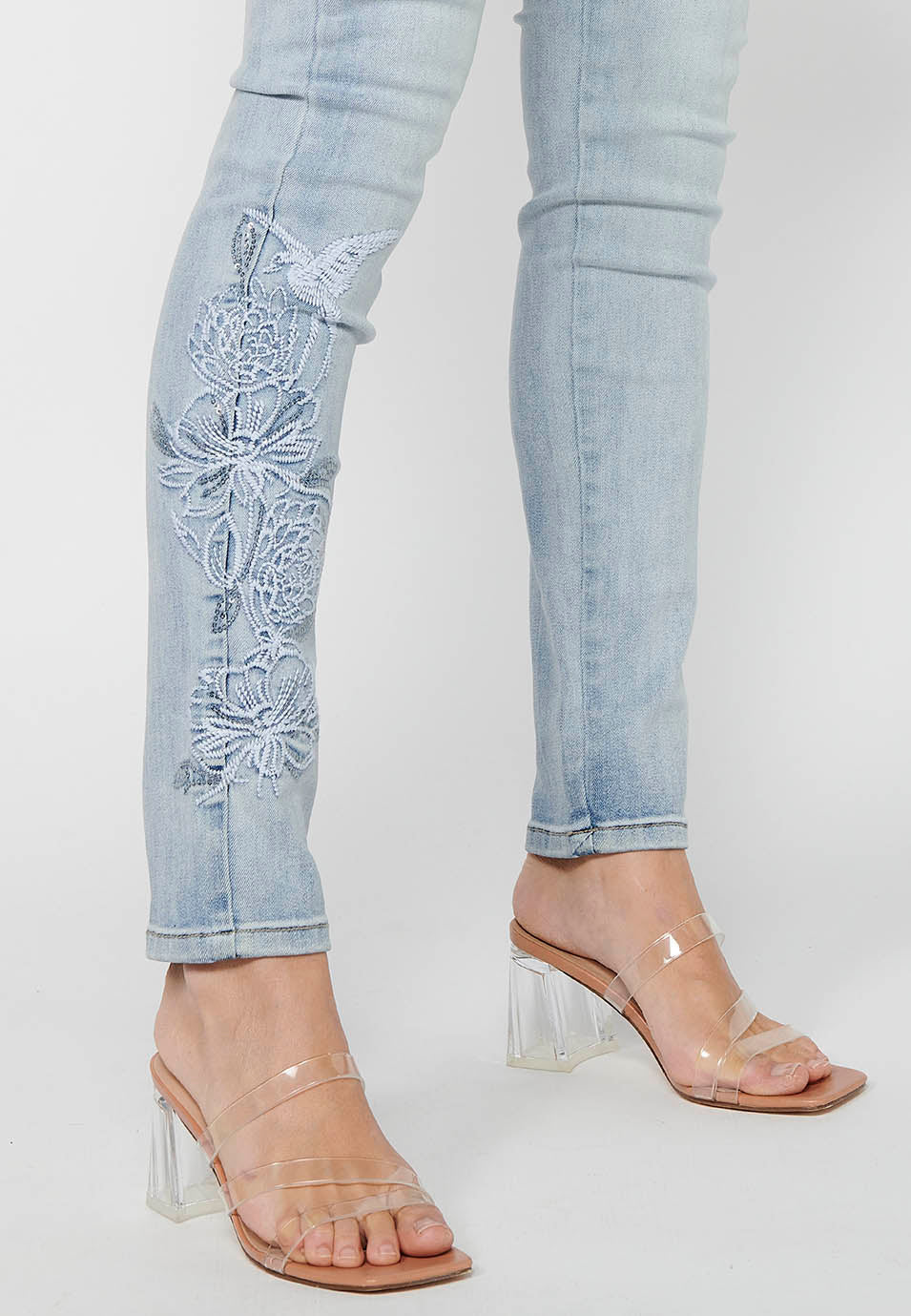 Pantalón largo slim con cierre delantero con cremallera y botón con detalles bordados de claro para mujer | moda actual
