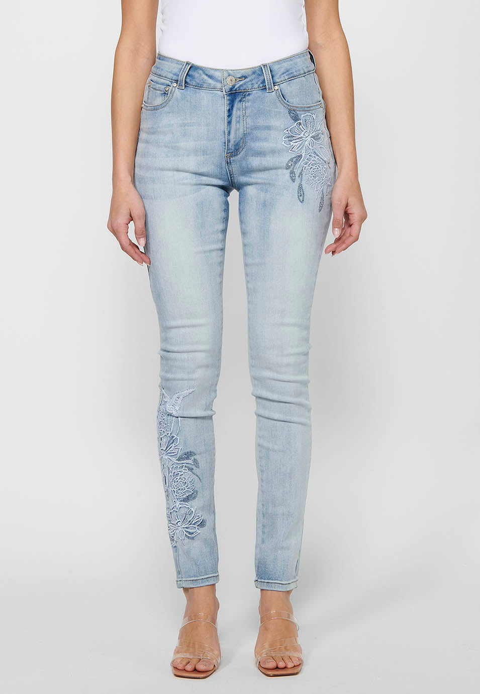 Pantalón largo slim con cierre delantero con cremallera y botón con detalles bordados de claro para mujer | moda actual