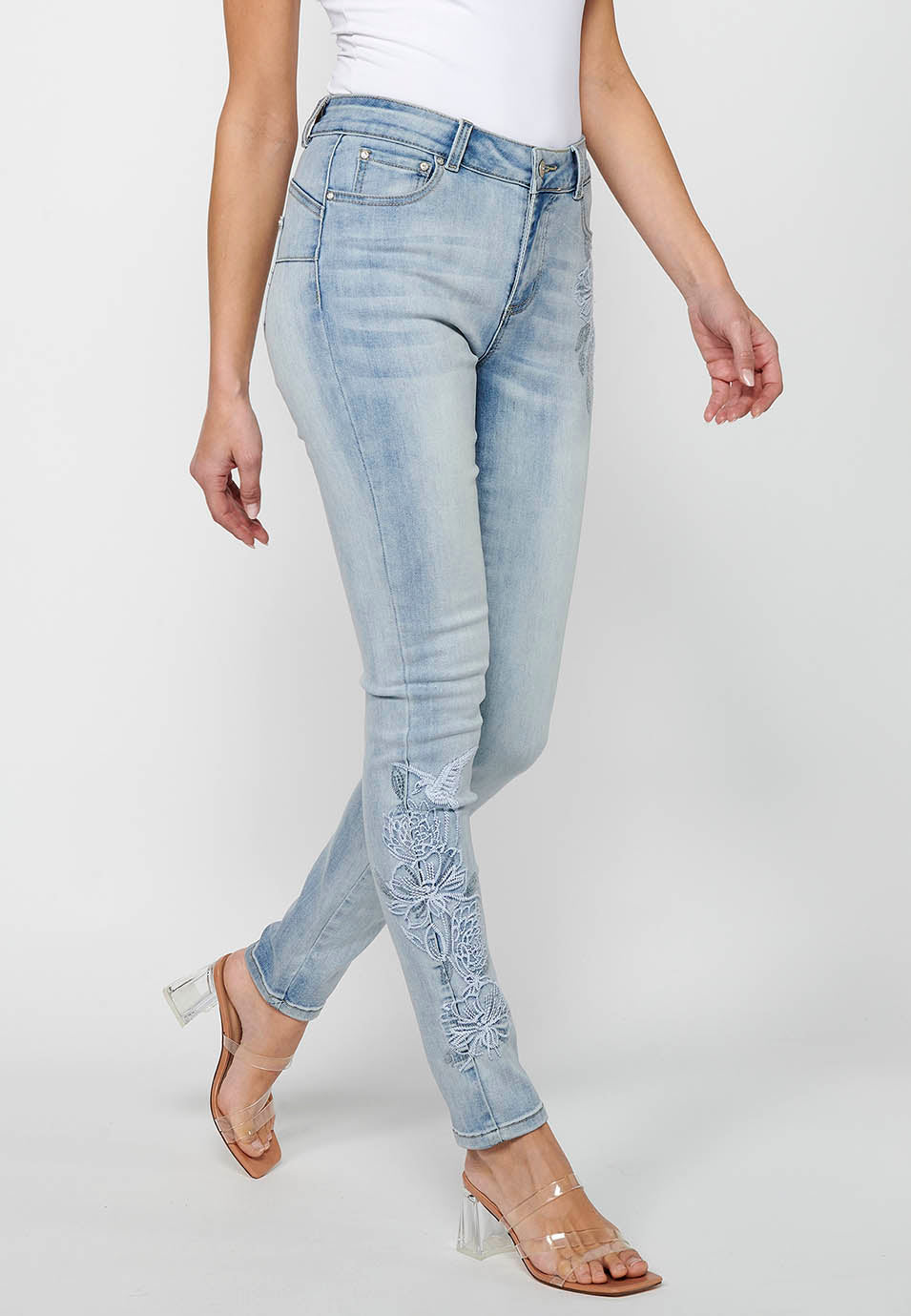 Pantalón largo slim con cierre delantero con cremallera y botón con detalles bordados de claro para mujer | moda actual