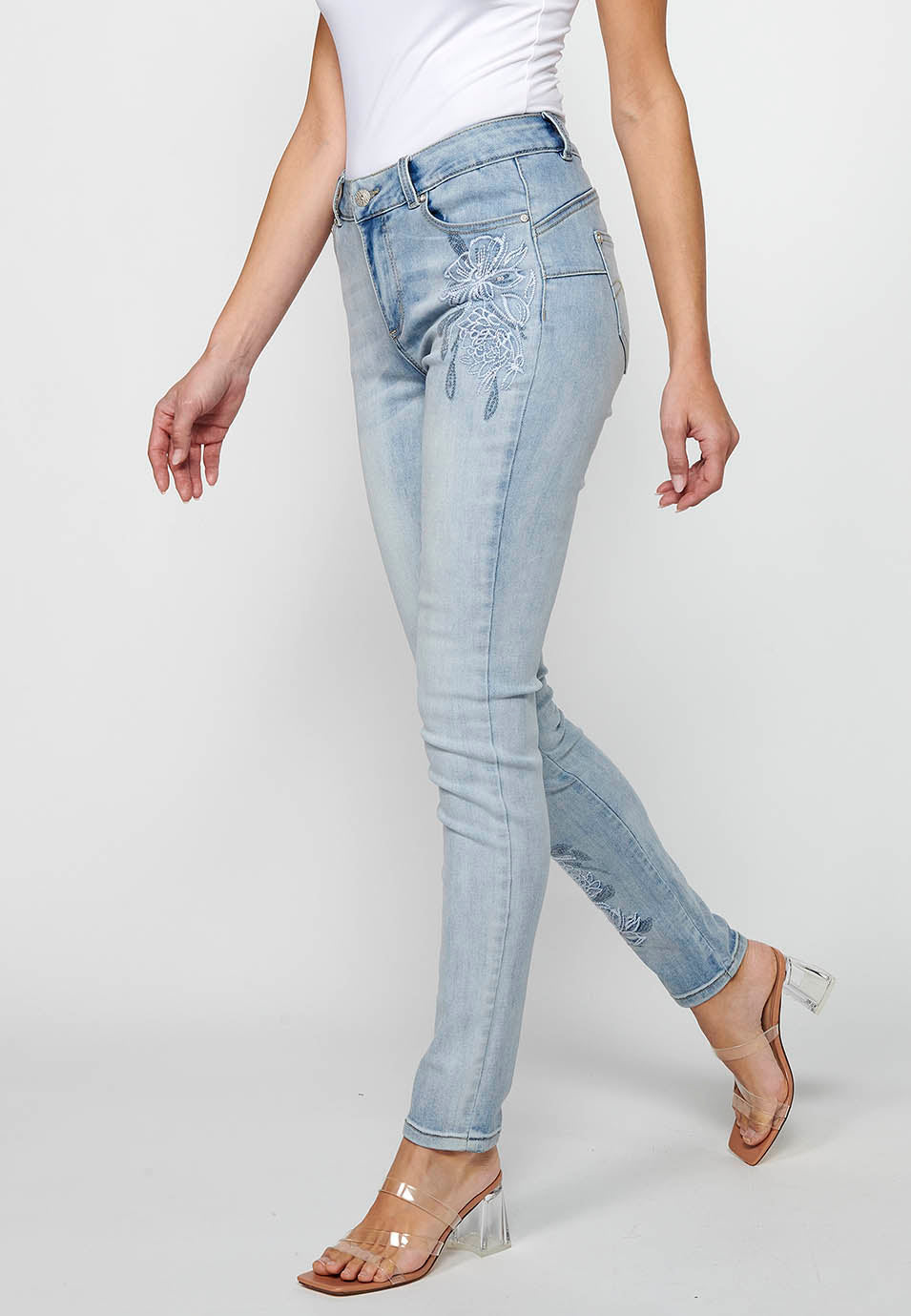 Pantalón largo slim con cierre delantero con cremallera y botón con detalles bordados de claro para mujer | moda actual