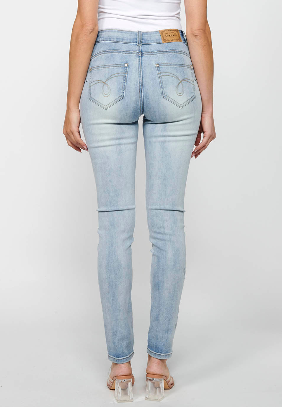Pantalón largo slim con cierre delantero con cremallera y botón con detalles bordados de claro para mujer | moda actual