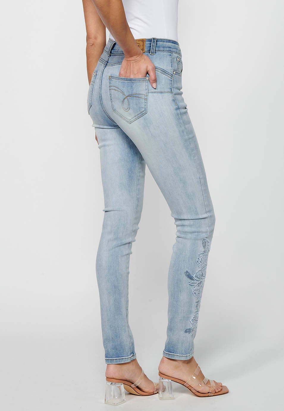 Pantalón largo slim con cierre delantero con cremallera y botón con detalles bordados de claro para mujer | moda actual