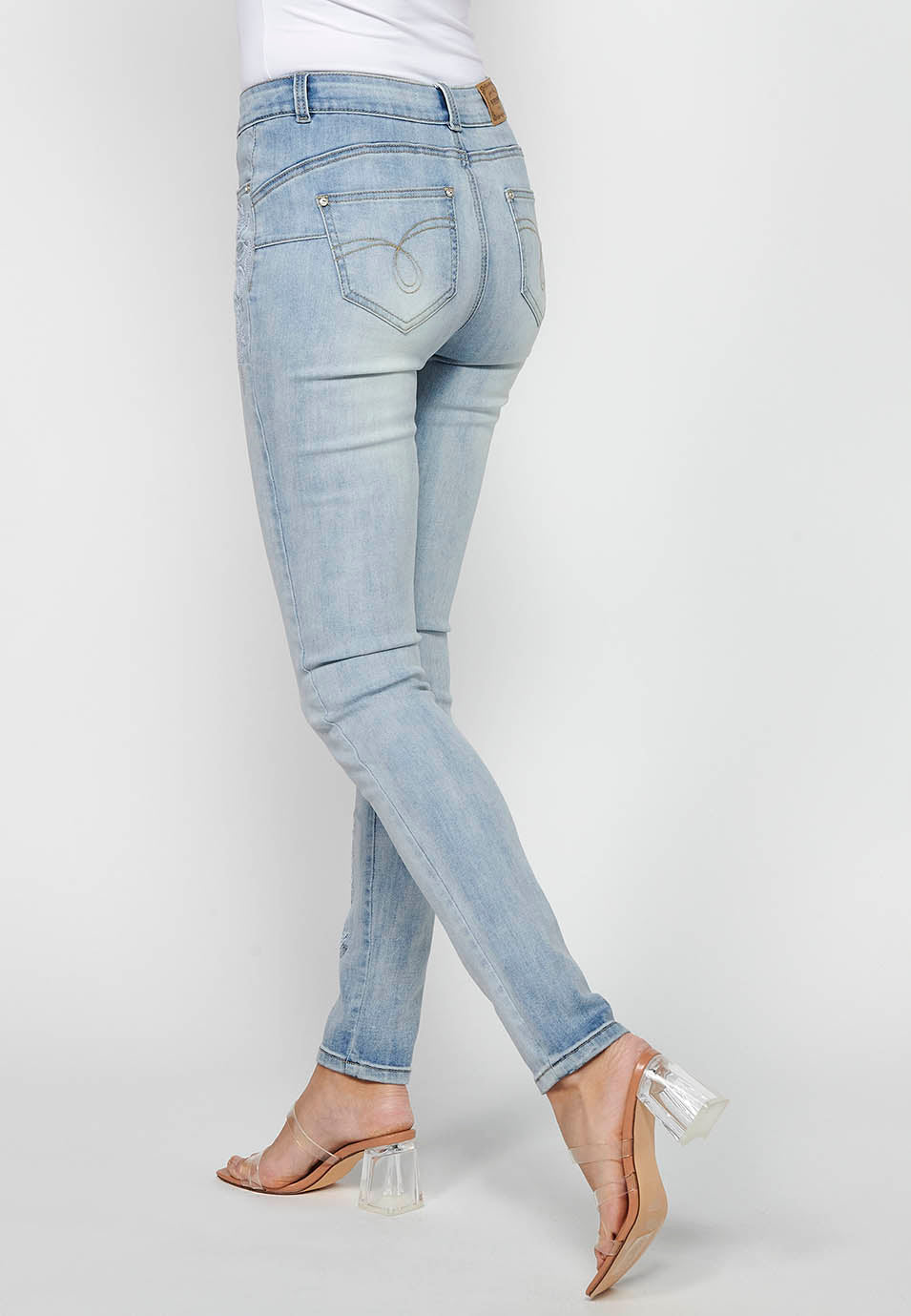 Pantalón largo slim con cierre delantero con cremallera y botón con detalles bordados de claro para mujer | moda actual