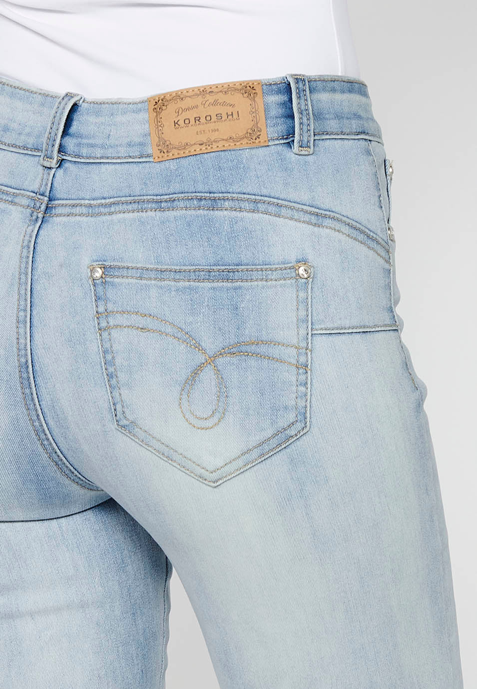 Pantalón largo slim con cierre delantero con cremallera y botón con detalles bordados de claro para mujer | moda actual