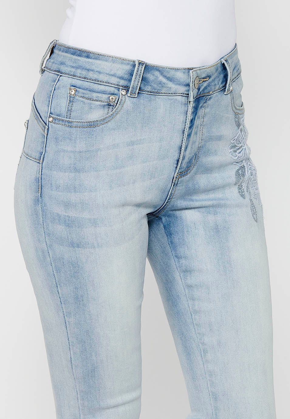 Pantalón largo slim con cierre delantero con cremallera y botón con detalles bordados de claro para mujer | moda actual