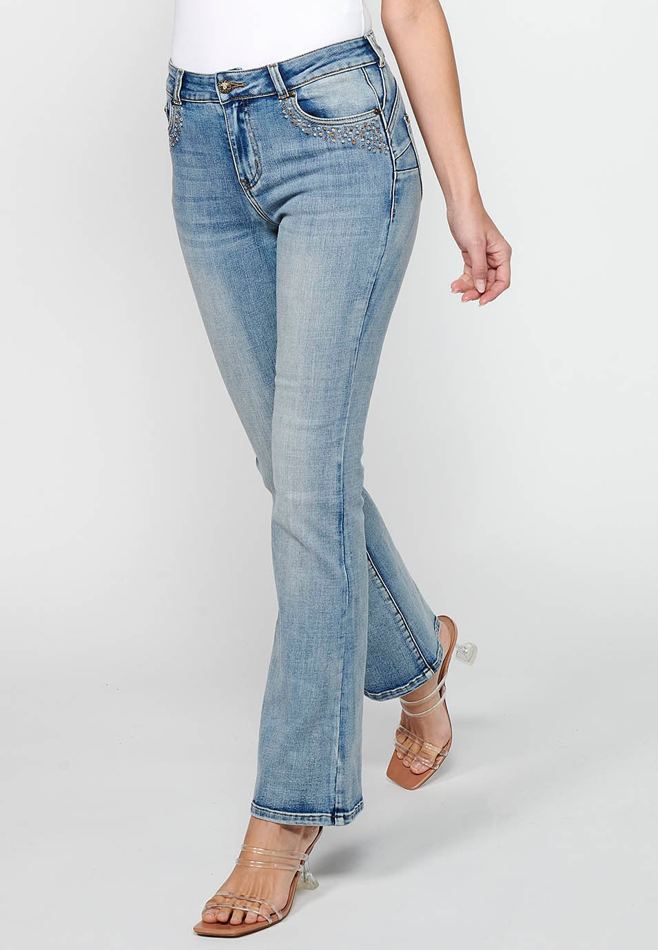Pantalón largo acabado en campana con cierre delantero con cremallera y botón con detalles de rotos de claro para mujer | moda actual