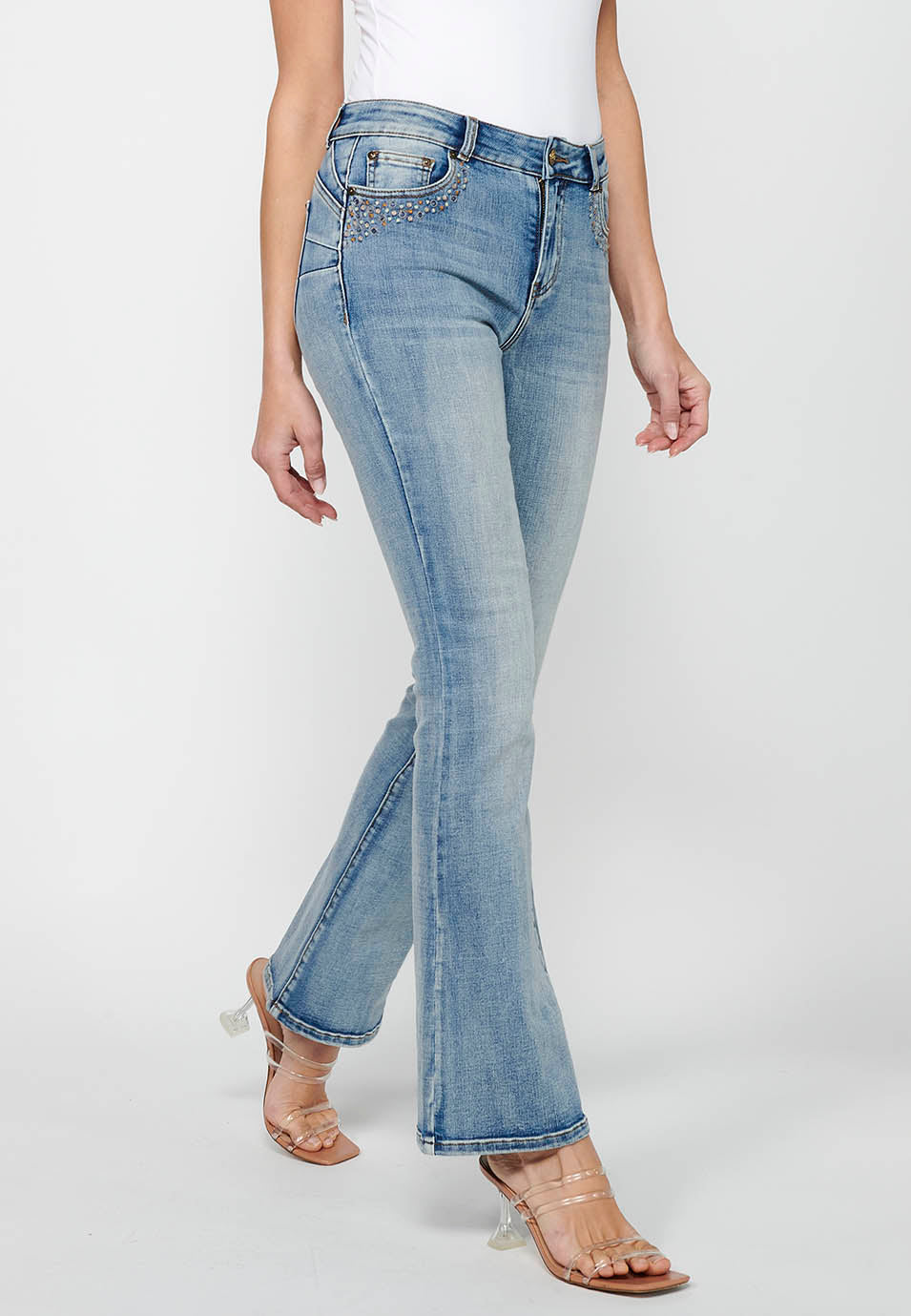 Pantalón largo acabado en campana con cierre delantero con cremallera y botón con detalles de rotos de claro para mujer | moda actual