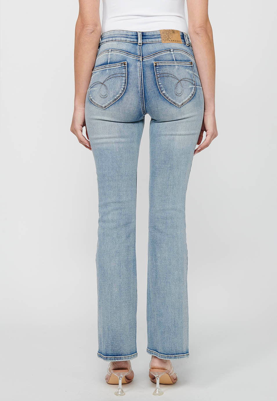 Pantalón largo acabado en campana con cierre delantero con cremallera y botón con detalles de rotos de claro para mujer | moda actual