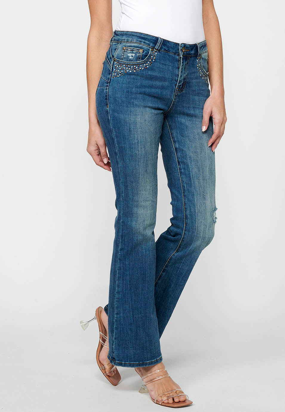 Pantalón largo acabado en campana con cierre delantero con cremallera y botón con detalles de rotos de claro para mujer | moda actual