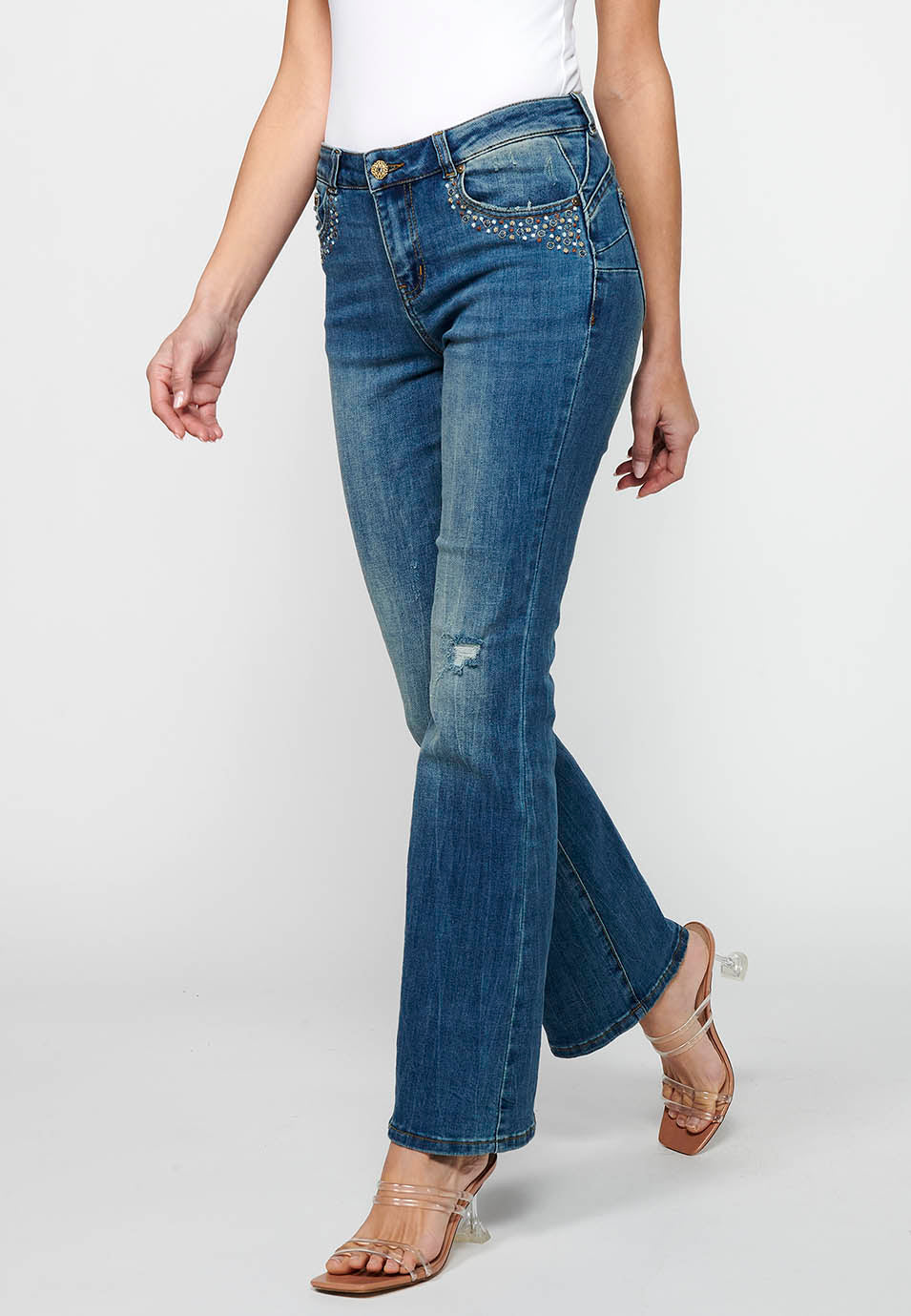 Pantalón largo acabado en campana con cierre delantero con cremallera y botón con detalles de rotos de claro para mujer | moda actual