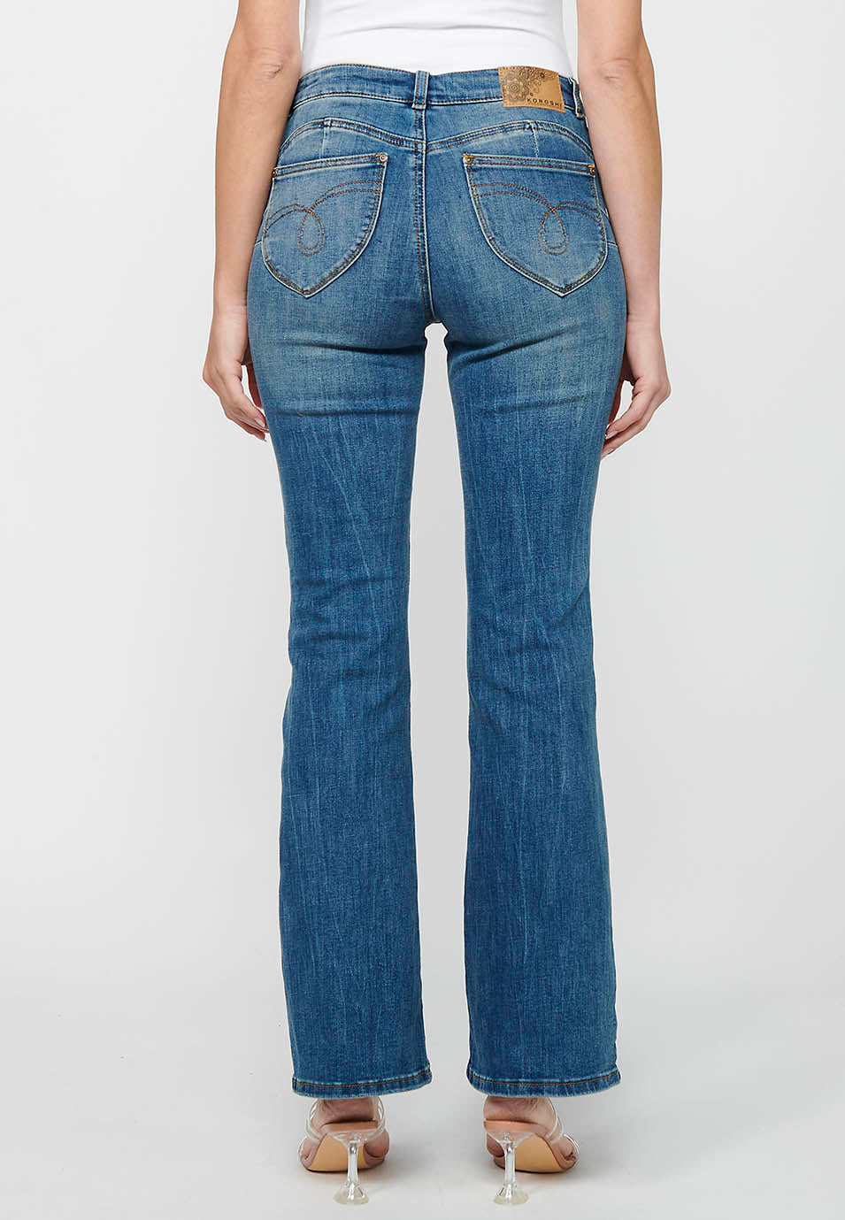 Pantalón largo acabado en campana con cierre delantero con cremallera y botón con detalles de rotos de claro para mujer | moda actual