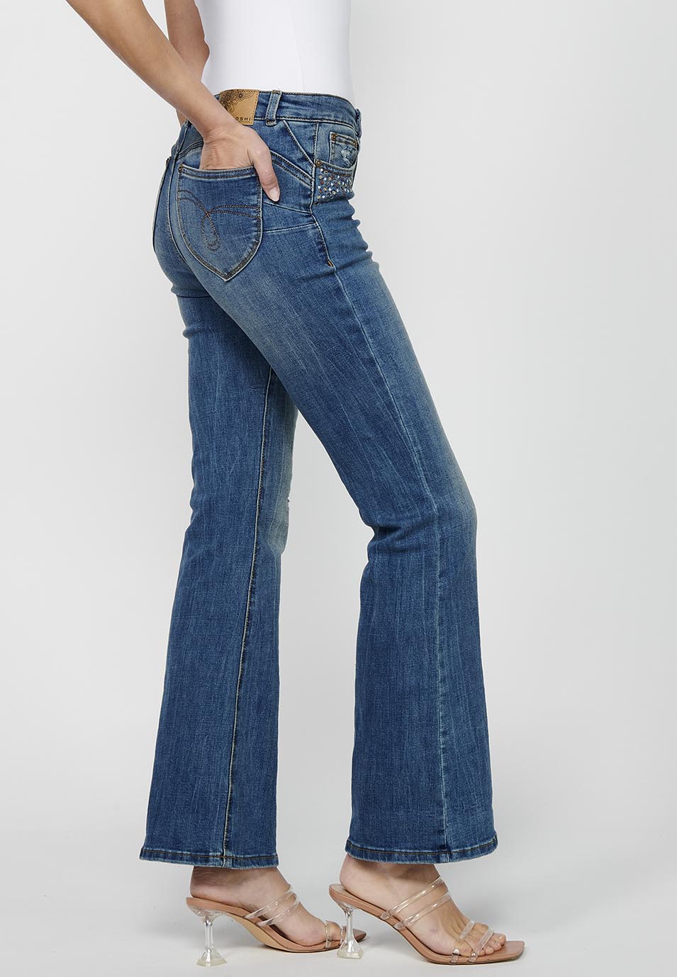 Pantalón largo acabado en campana con cierre delantero con cremallera y botón con detalles de rotos de claro para mujer | moda actual