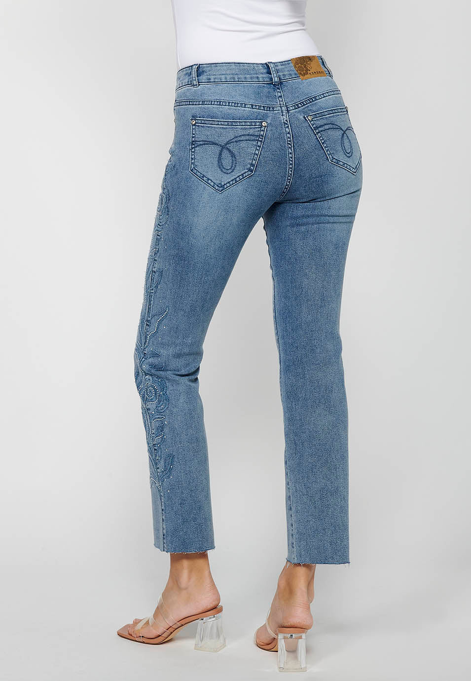 Pantalón denim largo campana con cierre delantero con cremallera y detalles bordados florales de claro para mujer | moda actual
