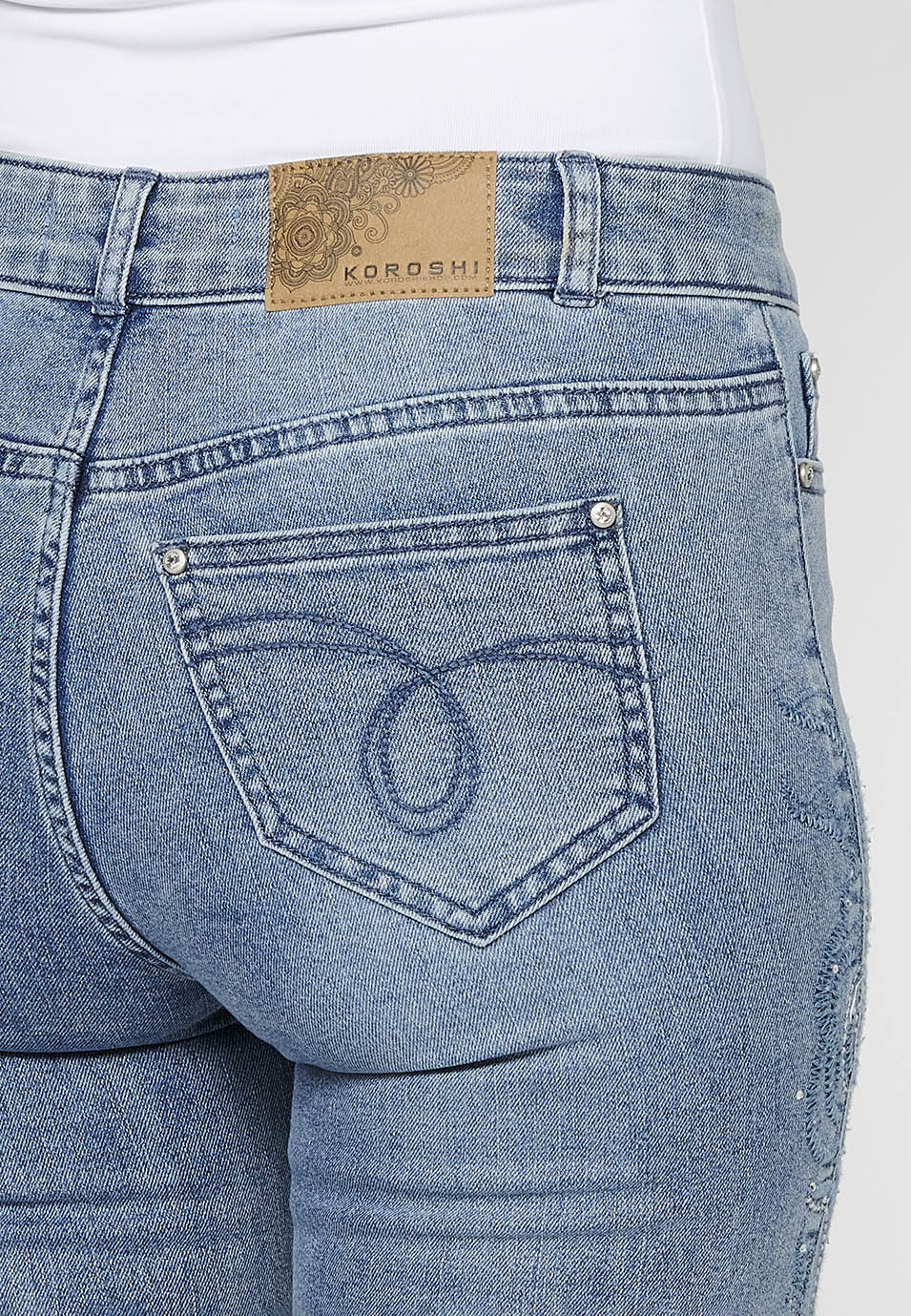 Pantalón denim largo campana con cierre delantero con cremallera y detalles bordados florales de claro para mujer | moda actual